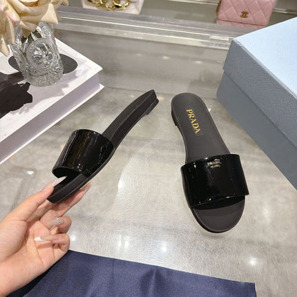 PRADA 26S LOGO EMBOSSED SLIDE SANDALS IN BLACK PATENT CALFSKIN