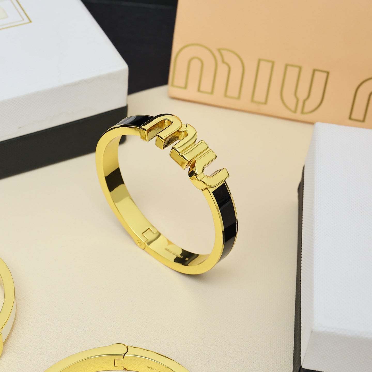 MIUMIU 26S LOGO HINGED BANGLE BRACELET WITH BLACK ENAMEL IN GOLD TONE METAL